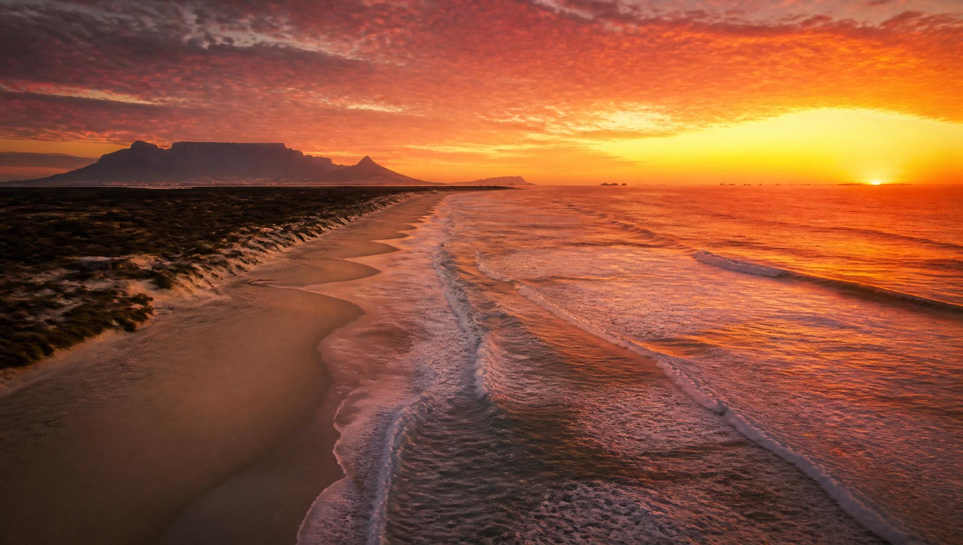 Melkbosstrand coastline at sunset with Table Mountain in distance